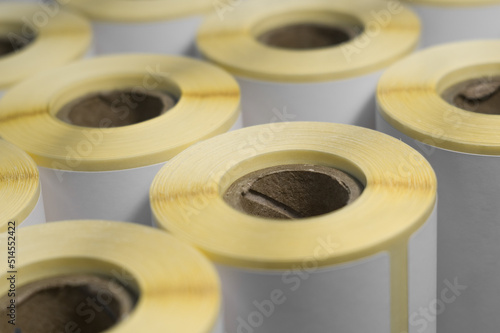 Rollers with a white self-adhesive label for printing labeling information. Ribbon with white label on cardboard spools. Products of the printing house. Selective focus