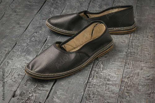 Slippers made of black leather for workers on a wooden background.