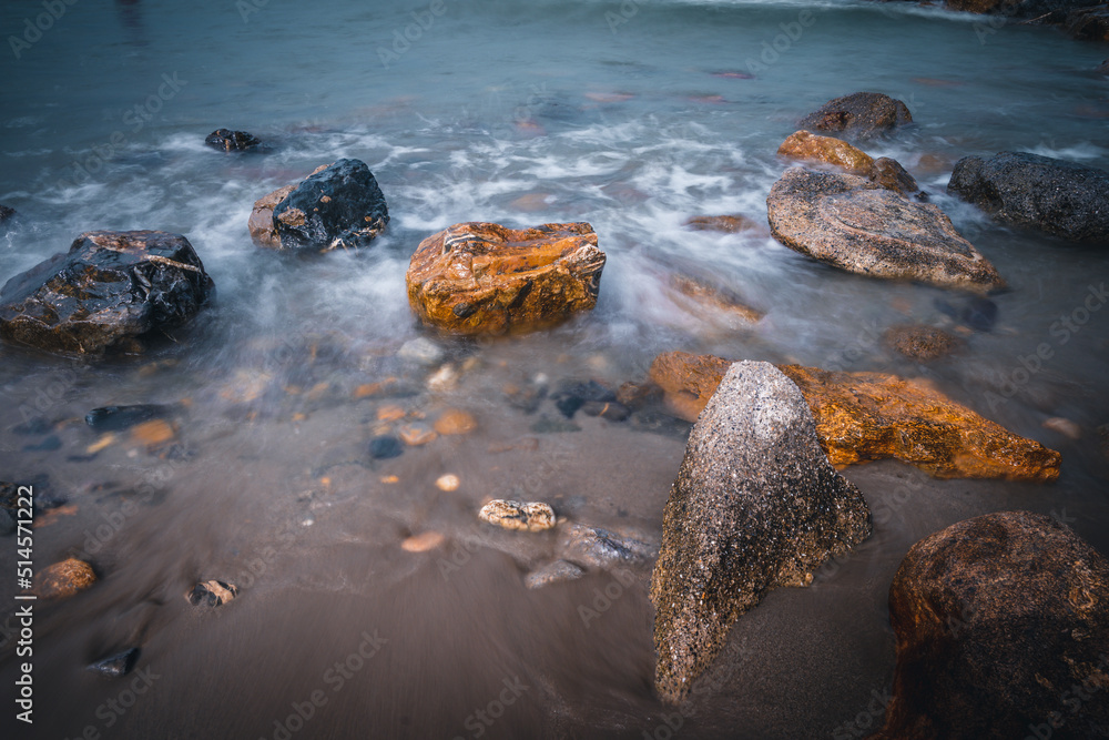 Beach on the Italian Riviera with sun, sea and stones in the sea water. Rough Sea and Foamy Waves on Shore at Mediterranean Coast in Sunrise Beach on the Italian Riviera with sun, sea and stones in the sea water. Rough Sea and Foamy Waves on Shore at Mediterranean Coast in Sunrise