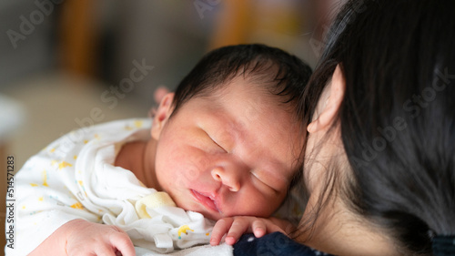 お母さんの抱っこでスヤスヤ眠る新生児