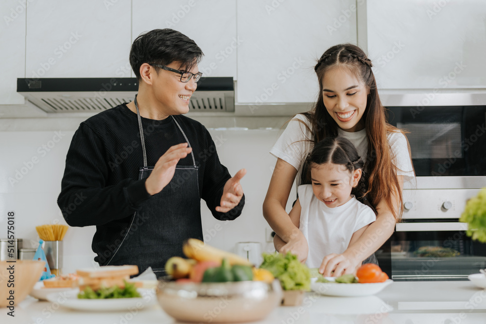 Asian family have fun cooking at home together. Happy dad and mom with little daughter cooking together in kitchen house. Family activities concept. Asian family have fun cooking at home together. Happy dad and mom with little daughter cooking together in kitchen house. Family activities concept.
