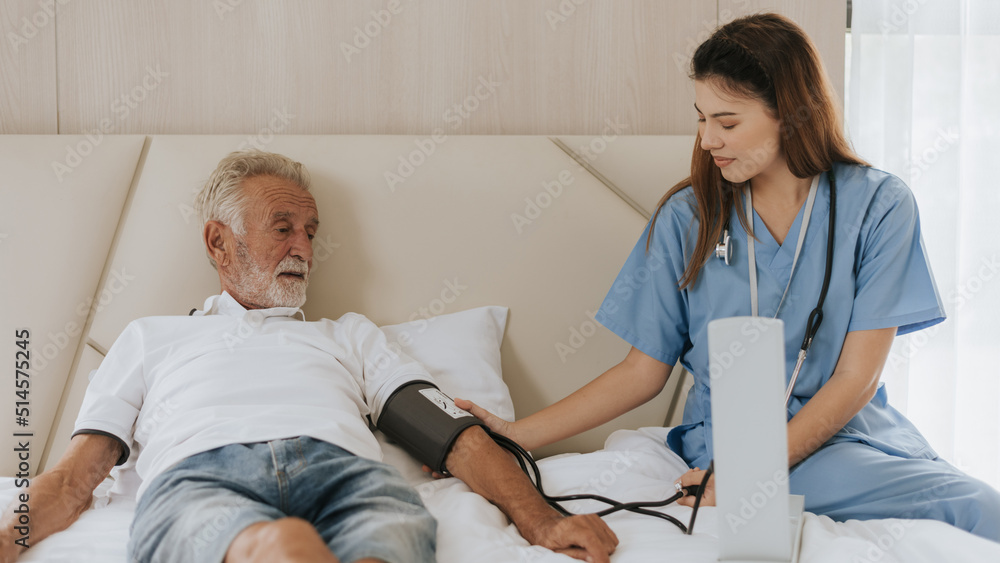 Obraz premium Asian nurse measuring blood pressure of elderly man at home. Young nurse helping senior man at home. Senior health care.