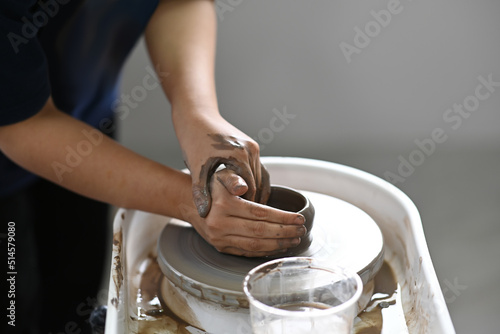 Cropped shot ceramicist creating handicraft crockery on the pottery wheel in workshop © Prathankarnpap