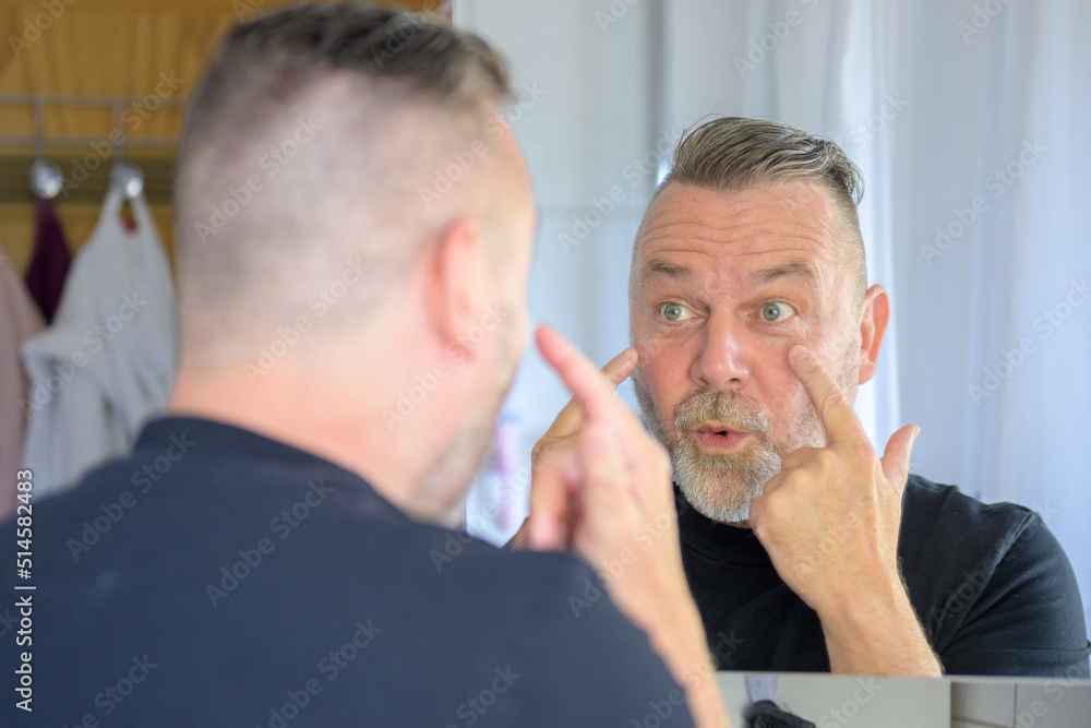 Man examining his face after applying hydration patches Man examining his face after applying hydration patches