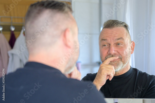 Senior man looking at his reflection with a rueful smile