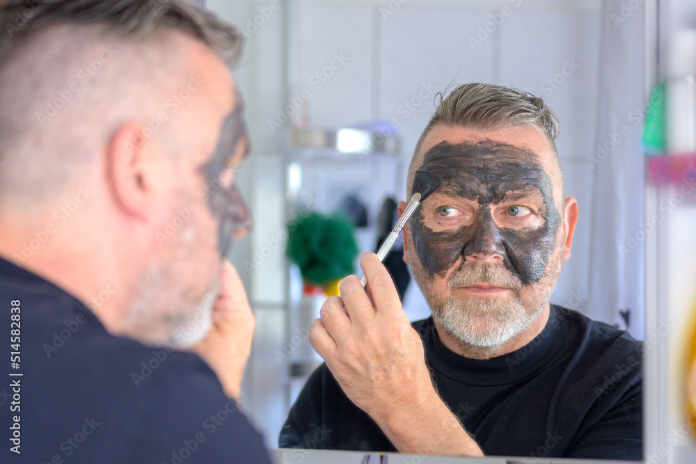 Senior man applying a cleansing cosmetic face mask Senior man applying a cleansing cosmetic face mask