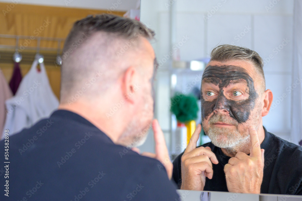 Fototapeta premium Middle-aged bearded man using a cosmetic face mask