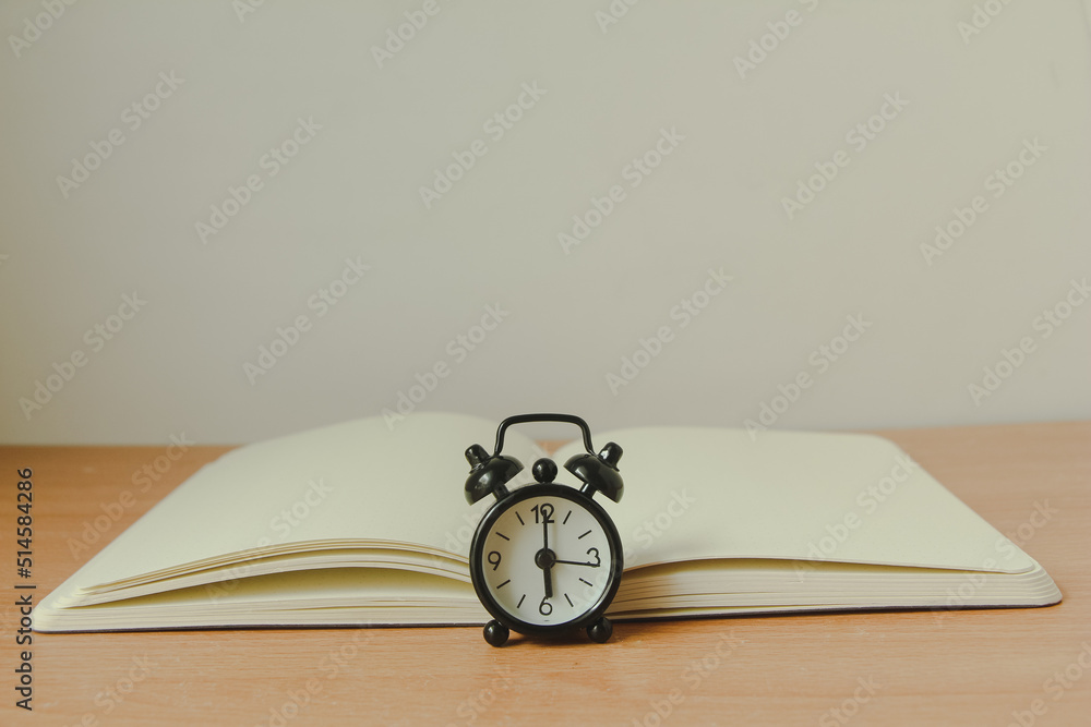 black alarm clock with notebook on wood background. Copy space. black alarm clock with notebook on wood background. Copy space.