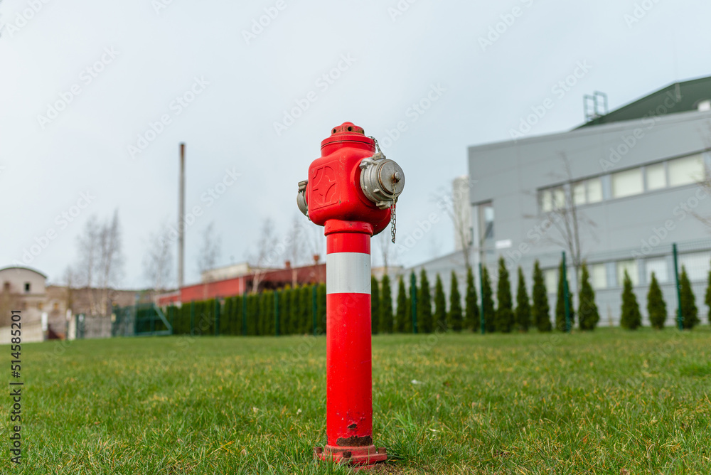 Single red fire hydrant on green lawn,near factory.Autumn,spring,summer overcast day.Copy space. Single red fire hydrant on green lawn,near factory.Autumn,spring,summer overcast day.Copy space.