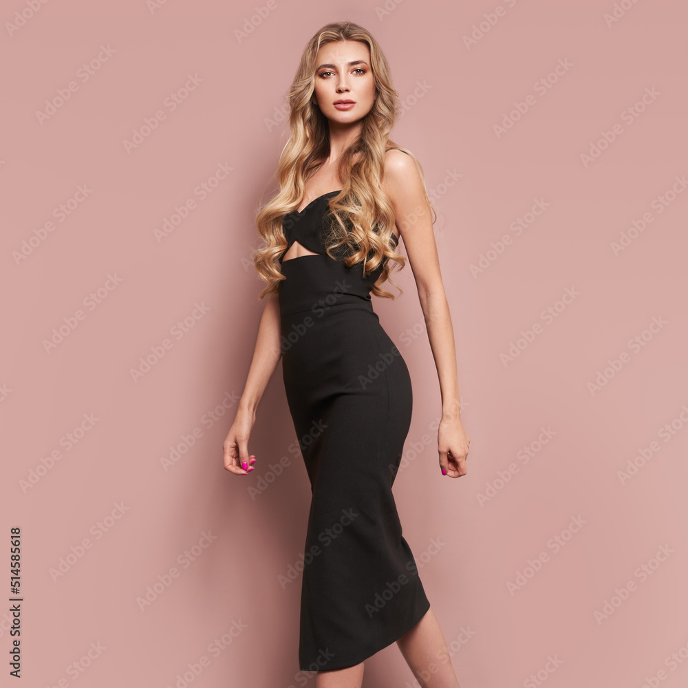 Portrait of gorgeous elegant sensual blonde woman wearing fashion black dress isolated on beige background. Model woman with long curly hairstyle. Care and beauty hair product Portrait of gorgeous elegant sensual blonde woman wearing fashion black dress isolated on beige background. Model woman with long curly hairstyle. Care and beauty hair product