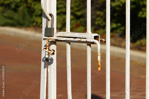 An iron padlock hangs on a closed gate
