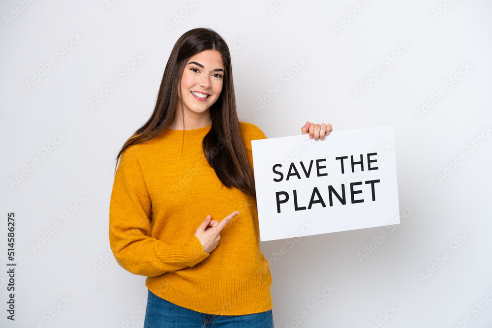 Young Brazilian woman isolated on white background holding a placard with text Save the Planet and pointing it Young Brazilian woman isolated on white background holding a placard with text Save the Planet and pointing it
