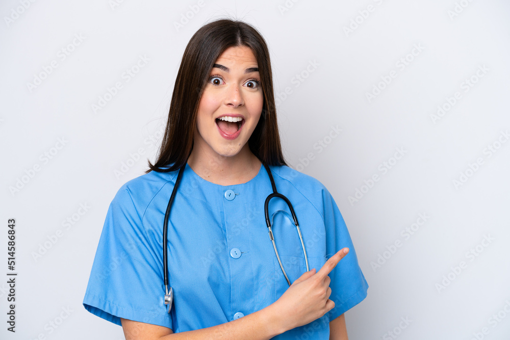 Young Brazilian nurse woman isolated on white background surprised and pointing side Young Brazilian nurse woman isolated on white background surprised and pointing side