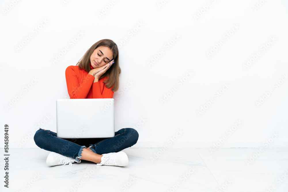Young caucasian woman sitting on the floor with a laptop making sleep gesture in dorable expression Young caucasian woman sitting on the floor with a laptop making sleep gesture in dorable expression
