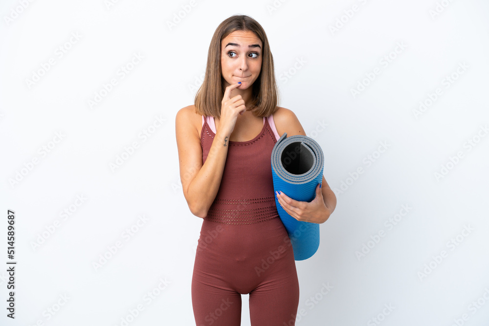Fototapeta premium Young sport caucasian woman going to yoga classes isolated on white background having doubts and thinking