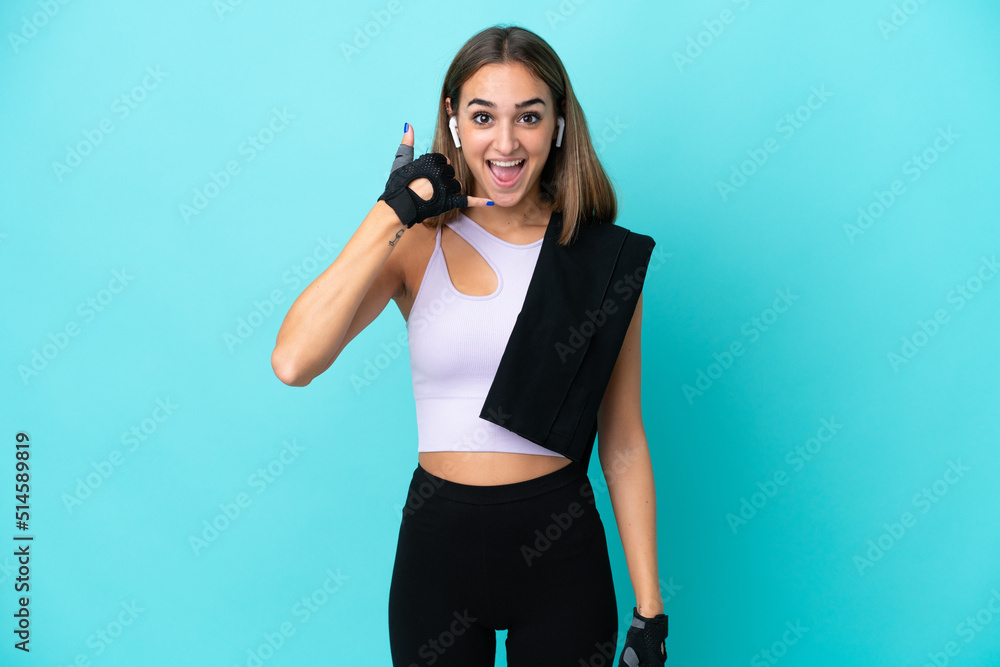 Young sport woman isolated on blue background making phone gesture. Call me back sign Young sport woman isolated on blue background making phone gesture. Call me back sign