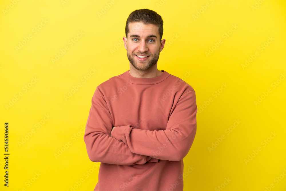 Handsome blonde man over isolated yellow background with arms crossed and looking forward Handsome blonde man over isolated yellow background with arms crossed and looking forward