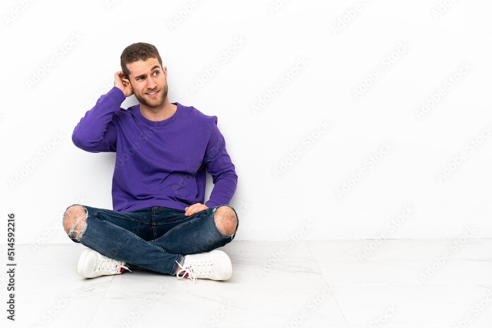 Young man sitting on the floor having doubts Young man sitting on the floor having doubts