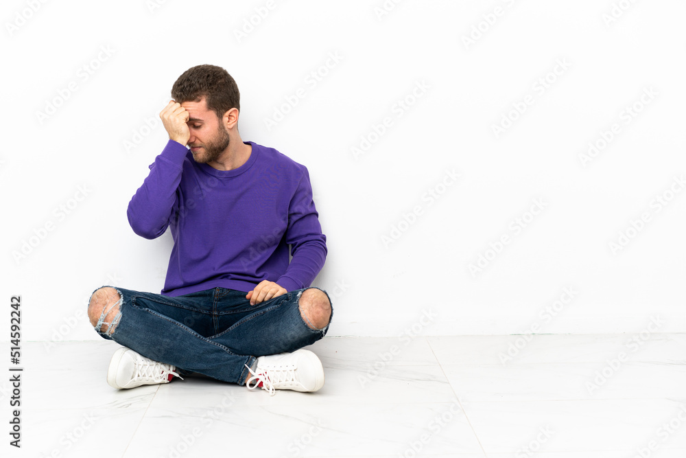 Young man sitting on the floor with headache Young man sitting on the floor with headache