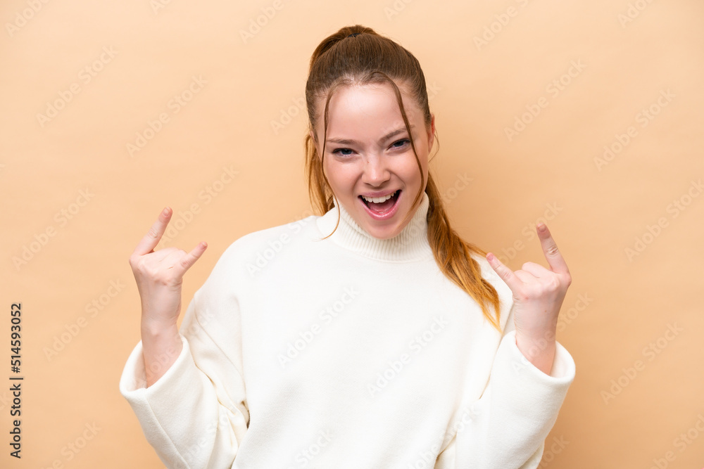 Young caucasian woman isolated on beige background making horn gesture Young caucasian woman isolated on beige background making horn gesture