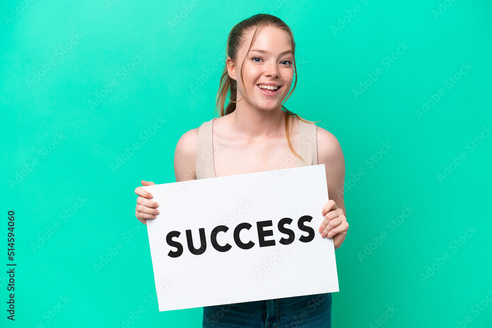 Young caucasian woman isolated on green background holding a placard with text SUCCESS with surprised expression Young caucasian woman isolated on green background holding a placard with text SUCCESS with surprised expression