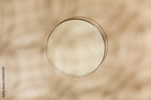 Hydrolyzed collagen powder in a Petri dish on a beige background with a shadow.  photo