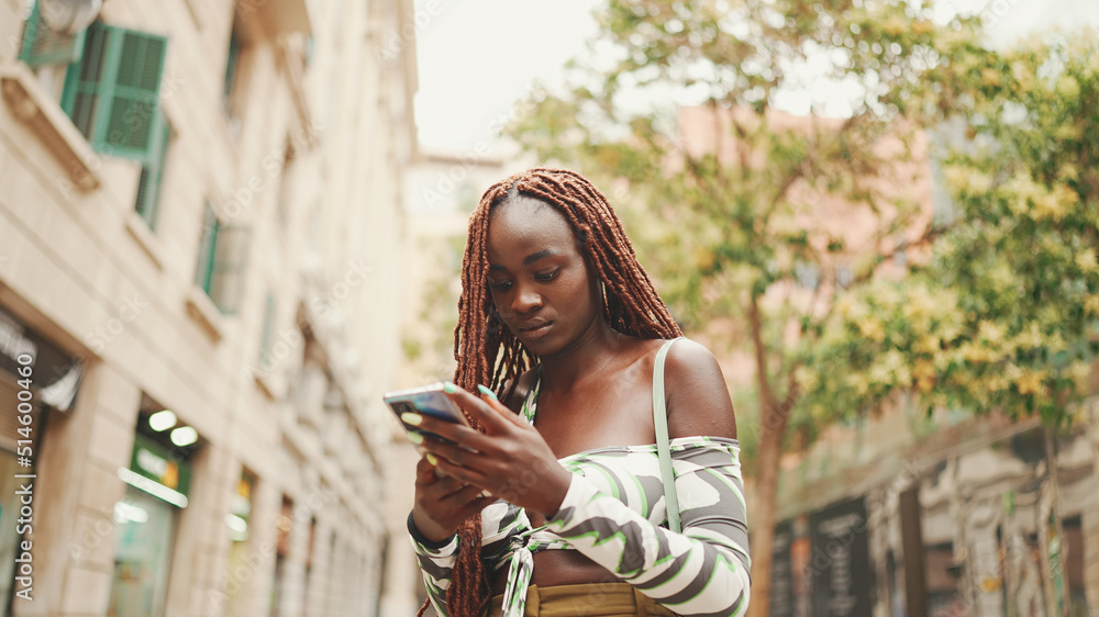 Gorgeous woman with African braids wearing top stands outside on the ...