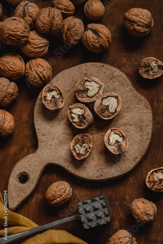 Open dried walnuts with nut opener on a wooden board. Walnut peeling process. Organic food with natural protein.