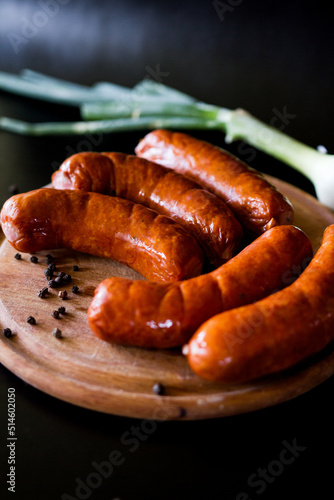 sausages on a plate. Sausages for grilling. Sausages board. Sausages on a black background. Tasty and juicy, natural grilled sausages.