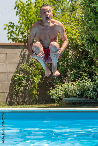 Foto Caucasian man with a funny expression takes a cannonball bomb dive in a swimming