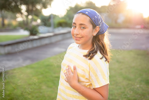 Portrait of cute happy teenage girl with long hair, wearing a blue bandana, yellow t-shirt. Caucasian. The concept of natural beauty, happiness, young skin, childhood. Summer time. Sunset. Soft focus.