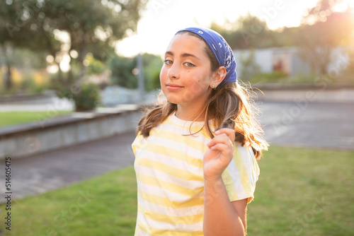 Portrait of cute happy teenage girl with long hair, wearing a blue bandana, yellow t-shirt. Caucasian. The concept of natural beauty, happiness, young skin, childhood. Summer time. Sunset. Soft focus.