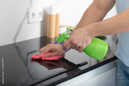 Close up shot of male hands holding bottle spray and cleaning the stove