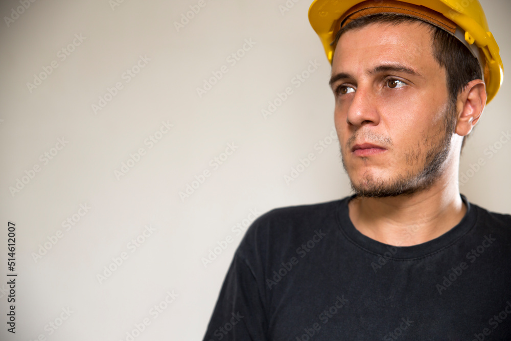 Worker with yellow safety hat for construction site work. Young white caucasian man with short hair and dark eyes. Worker with yellow safety hat for construction site work. Young white caucasian man with short hair and dark eyes.