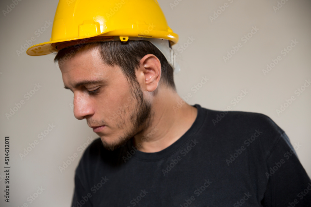 Worker with yellow safety hat for construction site work. Young white caucasian man with short hair and dark eyes. Worker with yellow safety hat for construction site work. Young white caucasian man with short hair and dark eyes.