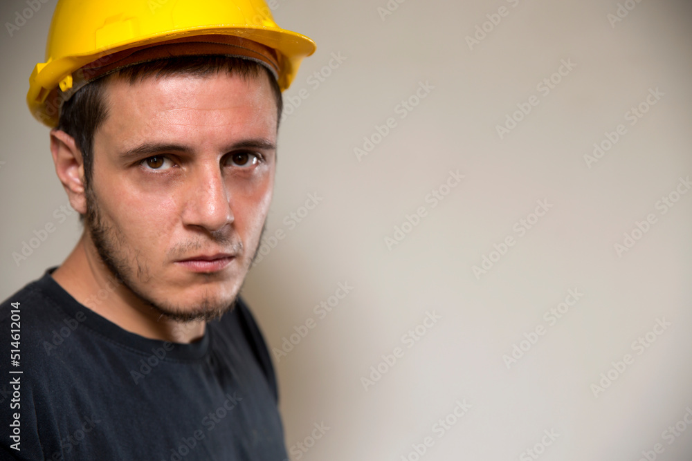 Worker with yellow safety hat for construction site work. Young white caucasian man with short hair and dark eyes. Worker with yellow safety hat for construction site work. Young white caucasian man with short hair and dark eyes.