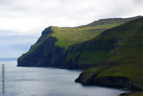 green-black cliffs under the white sky in the foreground blue ocean, Faroe Islands
