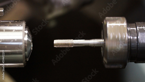 spinning drill bit in silver during processing against a black background