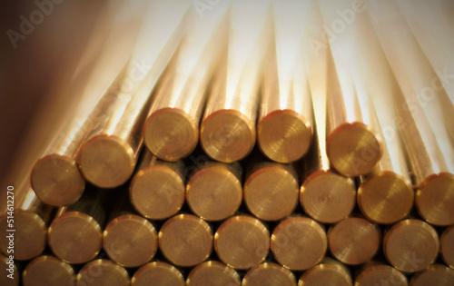 yellow brass rods stacked on top of each other in a pyramid, large depth of field