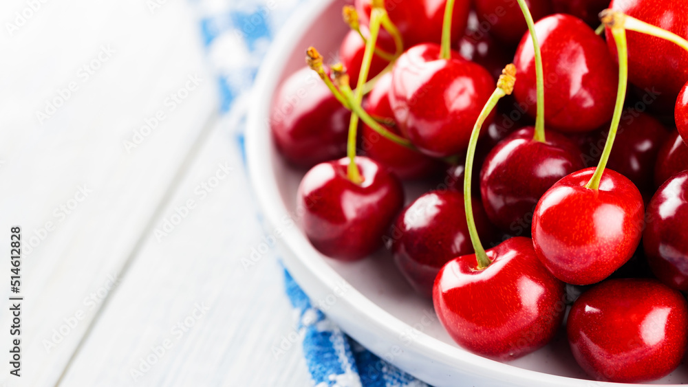 Red cherries on a white plate. Ripe sweet cherries on a wooden table. Red berries for diet food. Close-up Red cherries on a white plate. Ripe sweet cherries on a wooden table. Red berries for diet food. Close-up
