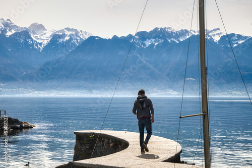Man walking down a pier with mountains in the background