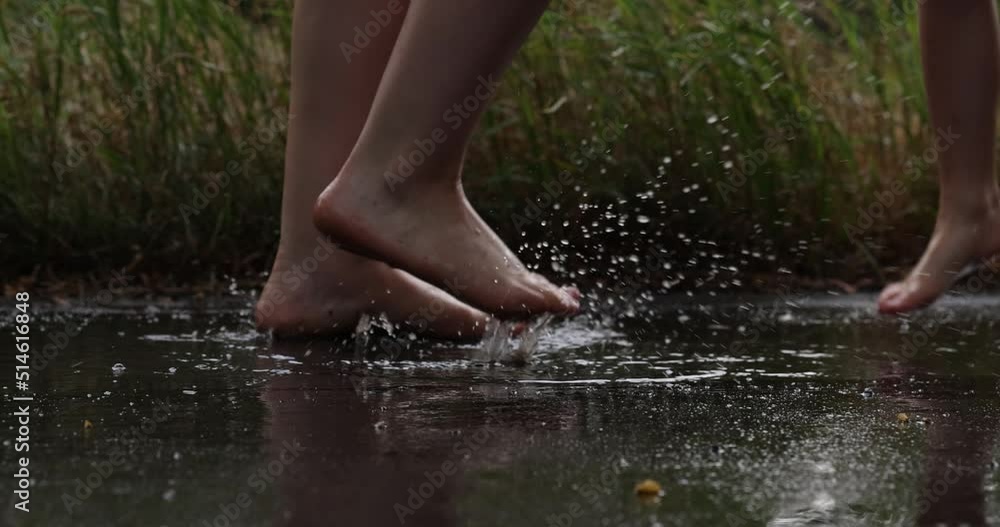 Girl jumping through the puddles barefoot in the rain. Happy childhood, joy. Girl jumping through the puddles barefoot in the rain. Happy childhood, joy.