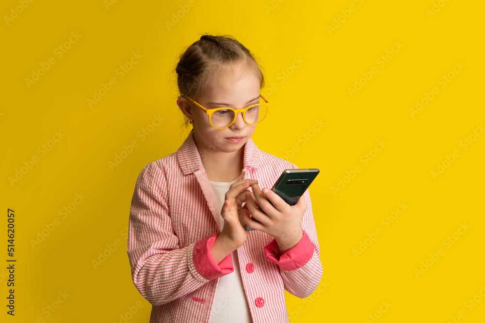 A girl with Down syndrome calls a friend on a smartphone A girl with Down syndrome calls a friend on a smartphone