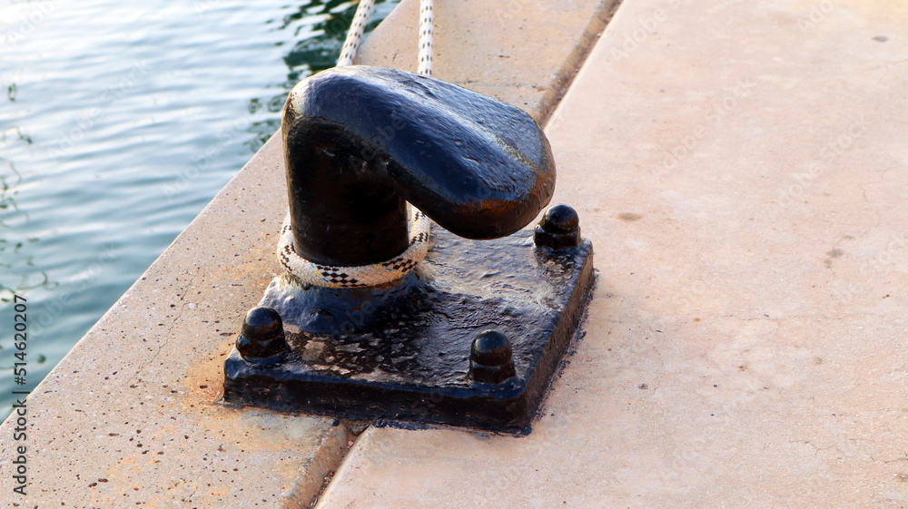 Mooring device for a yacht in a port made of metal for pulling a cable, black color. Denia, Spain Mooring device for a yacht in a port made of metal for pulling a cable, black color. Denia, Spain