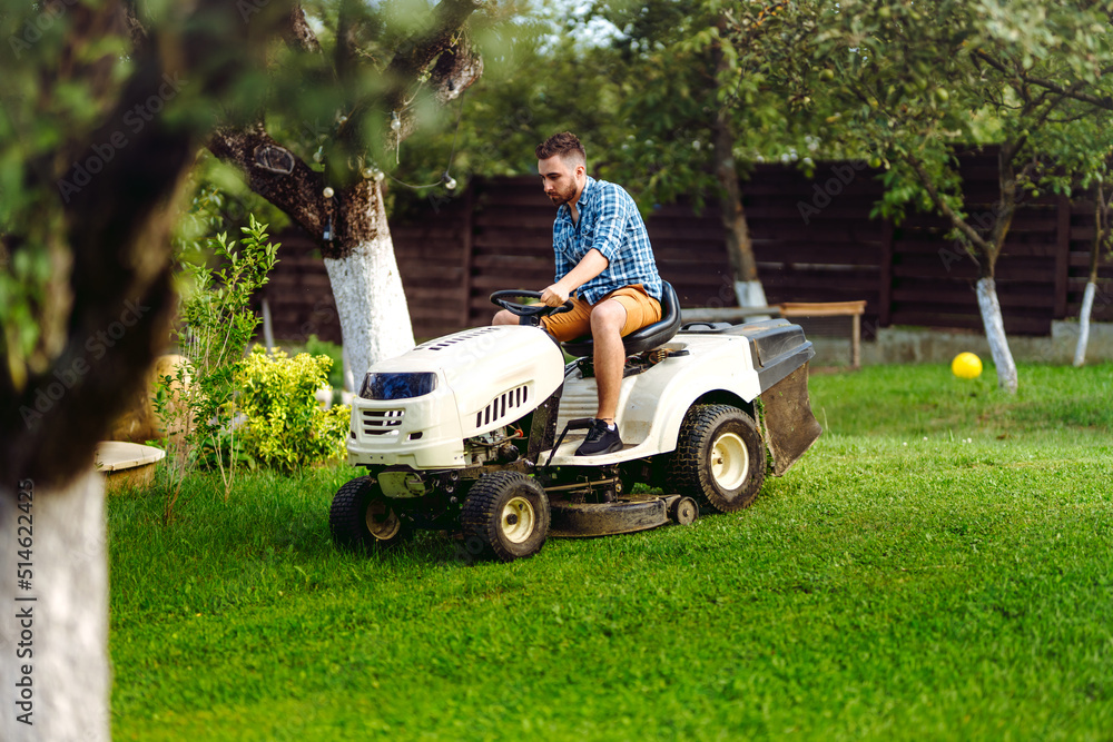 Portrait of gardener using a lawn mowing tractor for cutting grass. professional gardening details Portrait of gardener using a lawn mowing tractor for cutting grass. professional gardening details