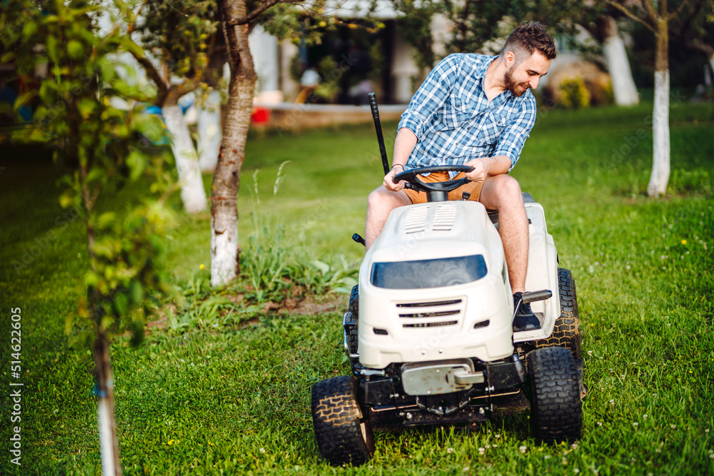 Fototapeta premium Landscaping details - portrait of gardener smiling and mowing lawn, cutting grass in garden