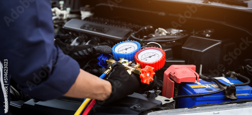 Close up hand of auto mechanic are to use measuring manifold gauge for filling car air conditioners. Concepts of fix and checking for repair service , Car service concept .