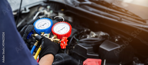 Close up hand of auto mechanic are to use measuring manifold gauge for filling car air conditioners. Concepts of fix and checking for repair service , Car service concept . © A Stockphoto