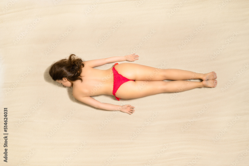 Top view of woman in red bikini lying and sunbathes on tropical Seychelles sand beach. Aerial, drone view Top view of woman in red bikini lying and sunbathes on tropical Seychelles sand beach. Aerial, drone view