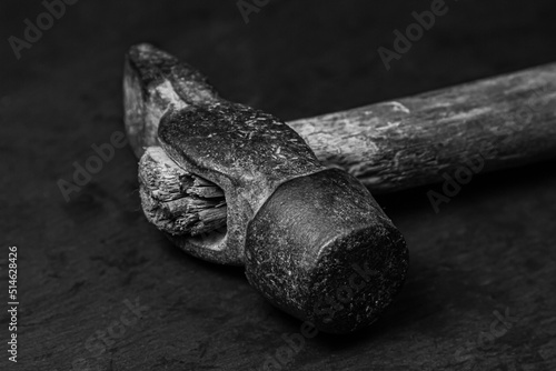 Old hammer on a black background. Black and white photograph of a working tool. old working tool